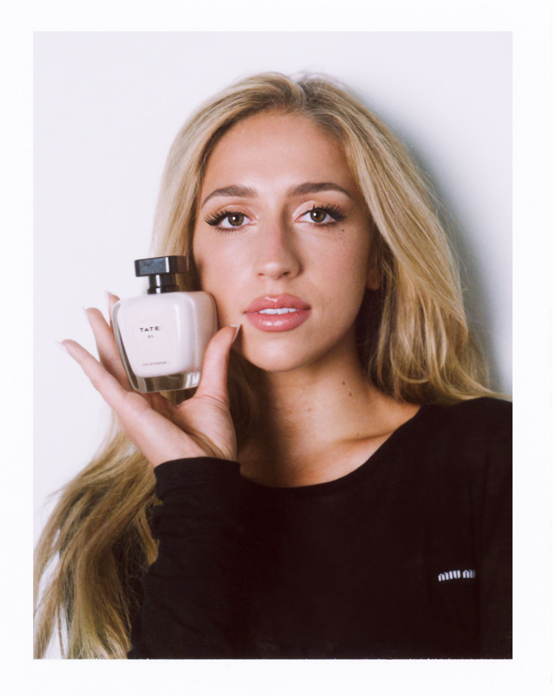 Tate McRae holding a bottle of her new fragrance.