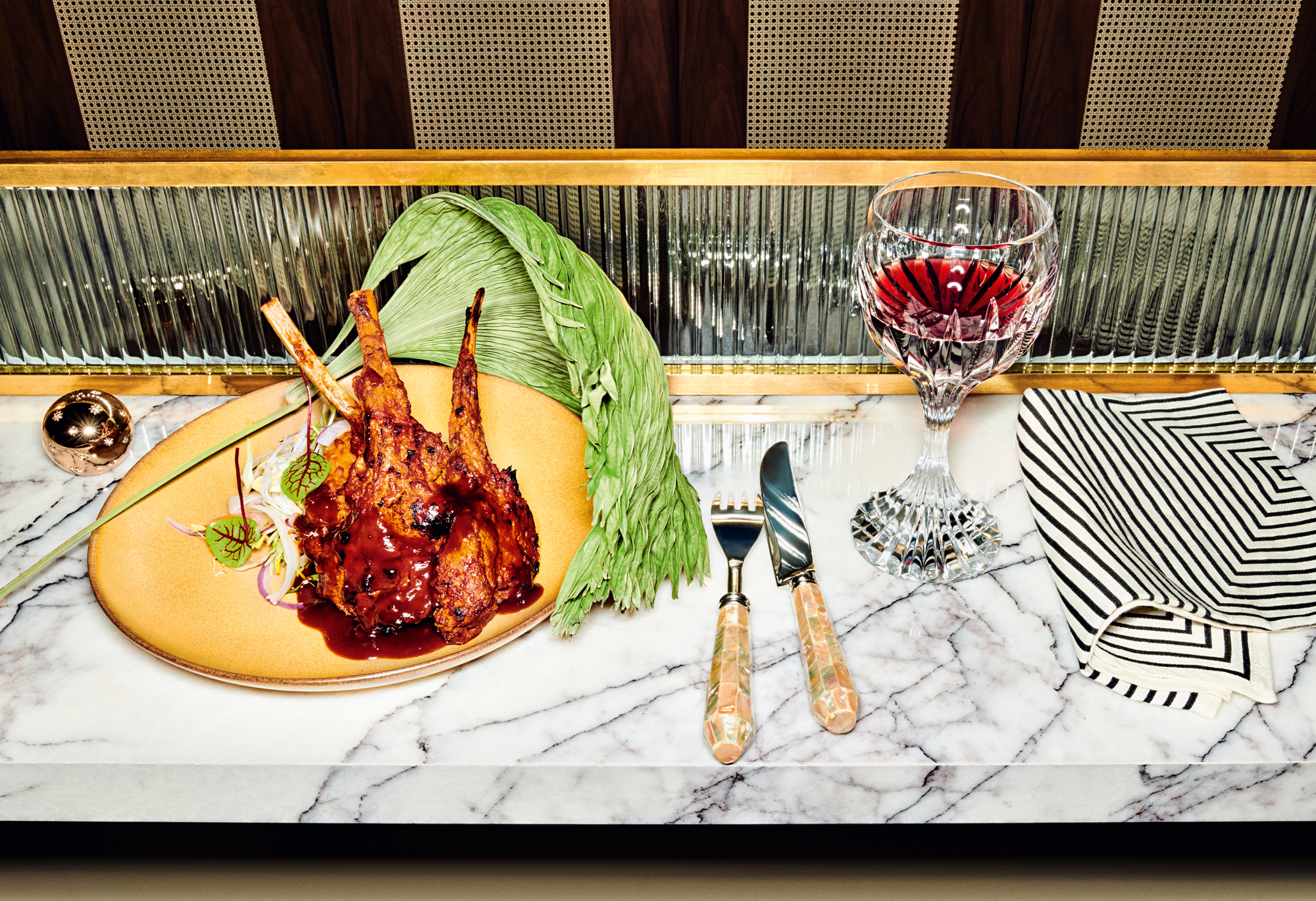 Tamarind lamb chops and red wine in glass on table laid for Mortlach whisky cocktails dinner