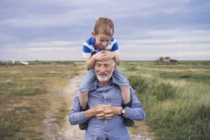 Young boy being carried by his grandad