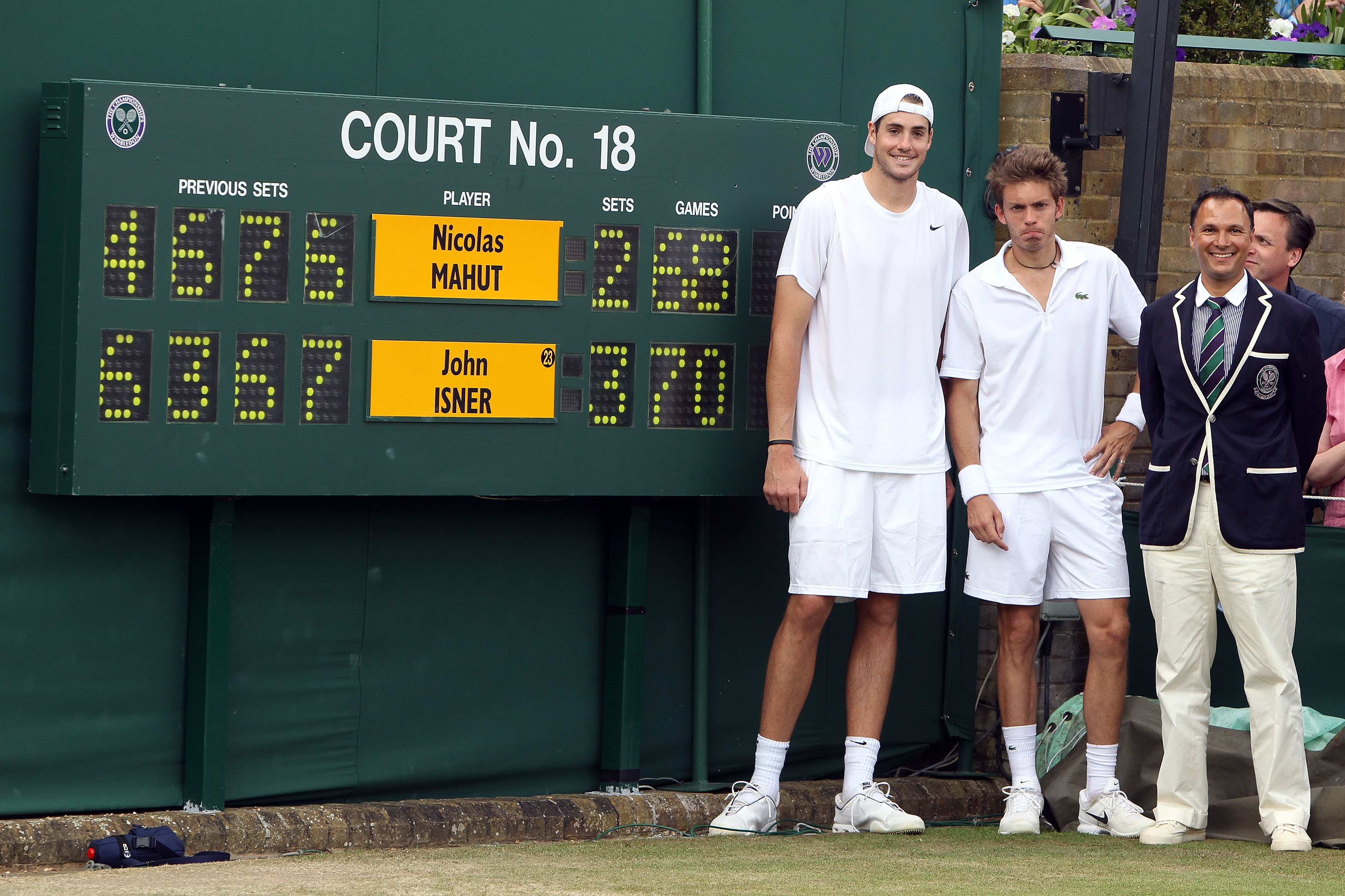 John Isner poses after winning on the third day of his first round match against Nicolas Mahut with Chair Umpire Mohamed Lahyani