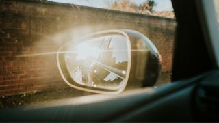 Car wing mirror with sunlight glinting off it