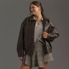 model wears gray sweater and skirt with dark brown faux leather bomber