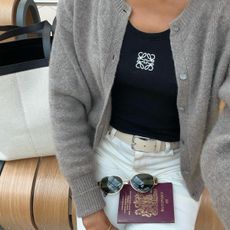 @symphonyofsilk wears a pair of white jeans, a black top and a grey cardigan whilst at the airport