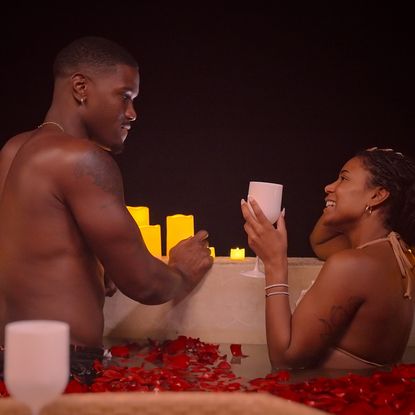demari and marissa on a date in a pool of red rose petals surrounded by candles in perfect match season 4
