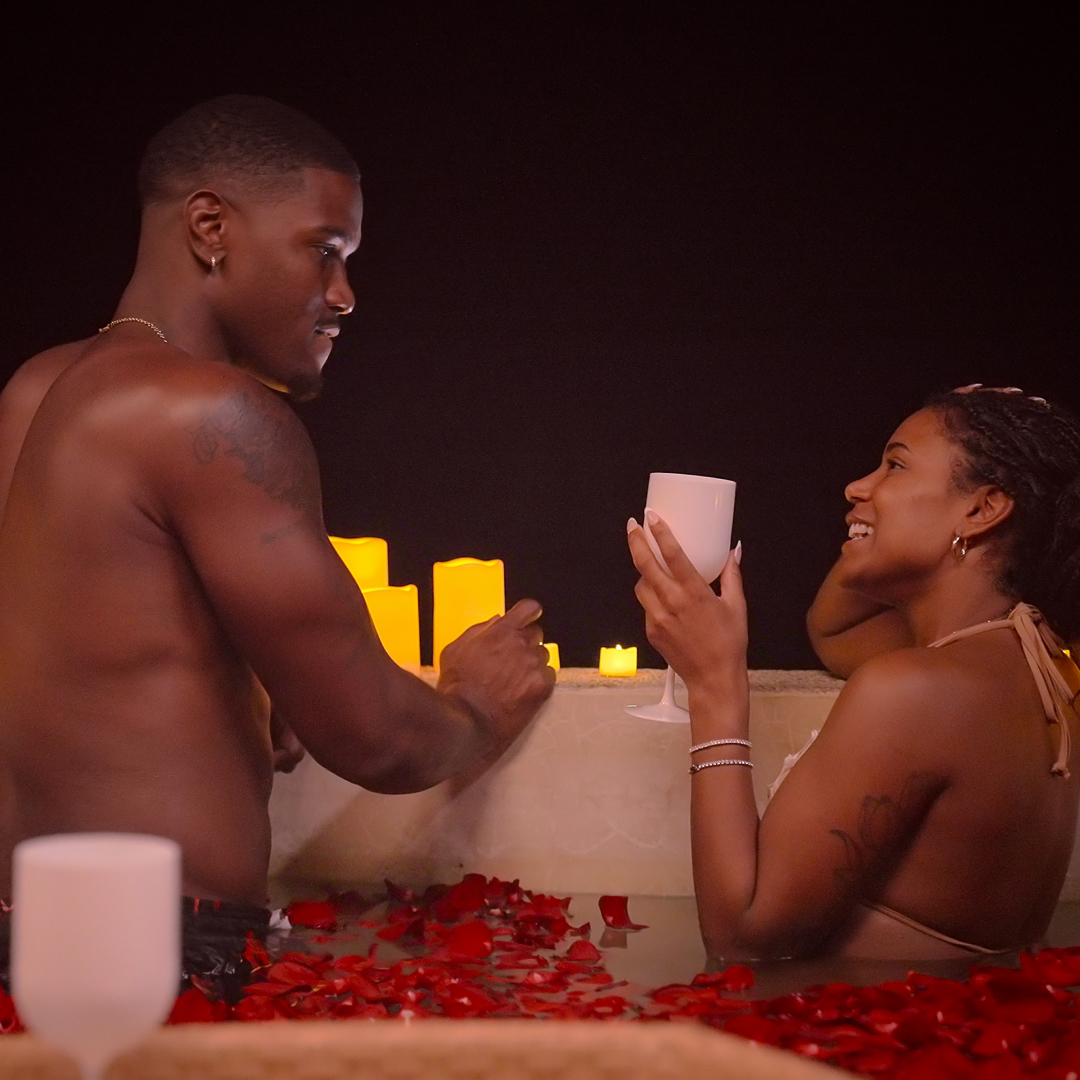 demari and marissa on a date in a pool of red rose petals surrounded by candles in perfect match season 4