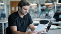 Investigative reporter Matt Shea wearing black t shirt looking at papers in an office in a scene from Tommy Robinson – Where's the Money Gone? on Channel 4 airing 9 Sept 2026