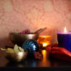 Christmas candles, a bowl of bay leaves, and other Christmas scents set out alongside some baubles on a dresser