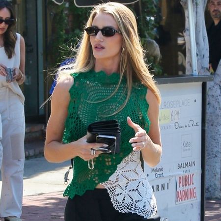 Rosie Huntington Whiteley wearing a crochet top, black sunglasses, and a black trousers.