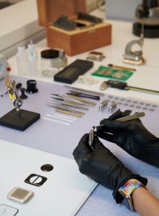Close up view of a model maker at Apple Park assembling a digital crown onto an Apple Watch Series 7