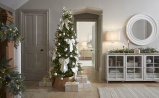 white hallway with a Christmas tree decorated in white bows and white baubles