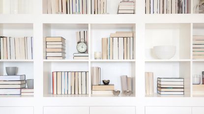 A white bookshelf with backwards books and small decor pieces