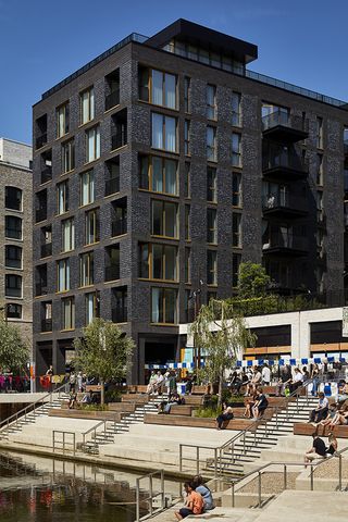 The Brentford Project showing brick residential blocks with large balconies and warehouse inspired streets and public spaces that step down to the water