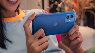 blue variant of the Moto G54 in the hand