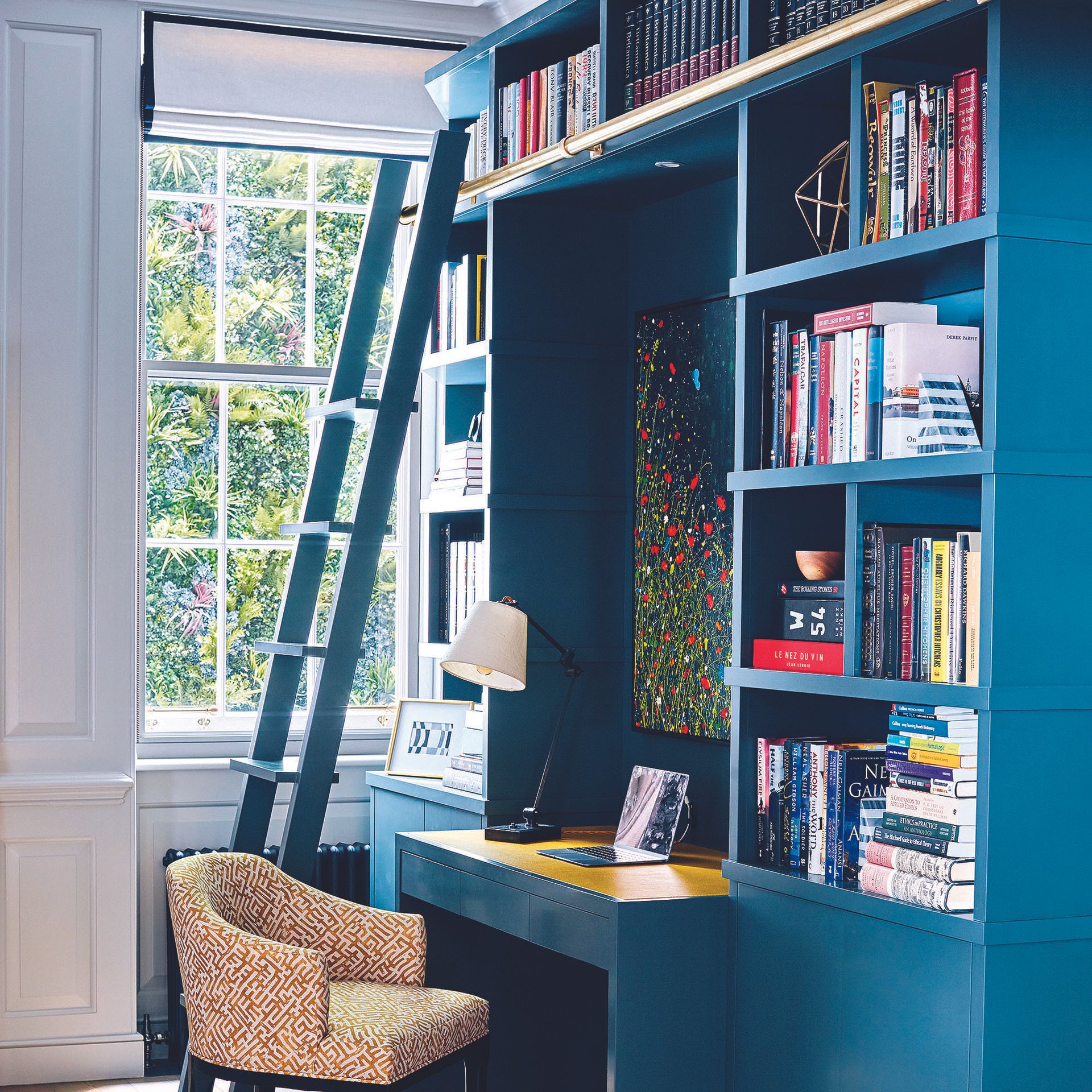 Home office with built-in blue wall storage unit with ladder.