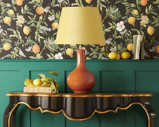 lamp on a black side table set against citrus wallpaper