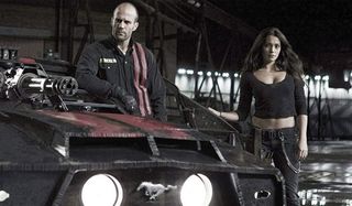 Death Race Jensen and Case stand next to their car in the garage