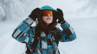 best hiking gloves: hiker adjusting hood in winter