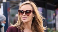 Amanda Holden wearing a burgundy coat and matching burgundy sunglasses 