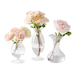 three clear glass bud vases holding flowers