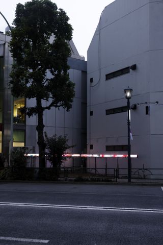 A narrow illuminated banner running alongside a building in a road.