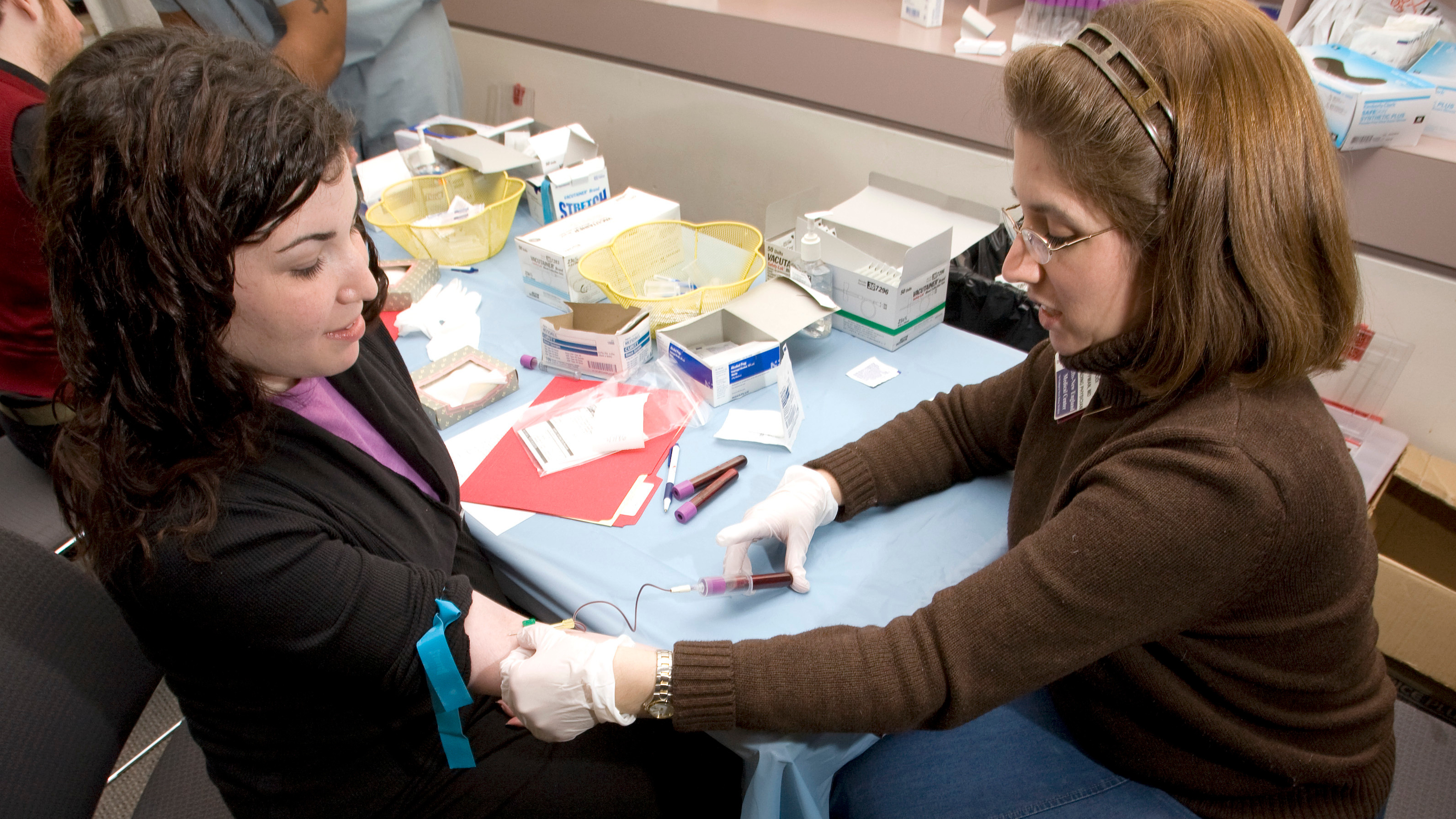 A doctor takes blood from a woman's arm