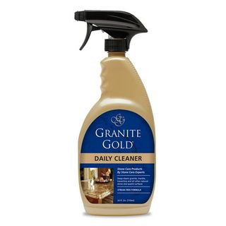 A gold bottle of Granite Gold Daily Cleaner with black spray lid and blue label