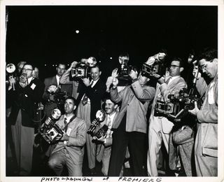 A black and white image of a crowd of photographers each with cameras in hand with the annotation 'photographers of premiere'