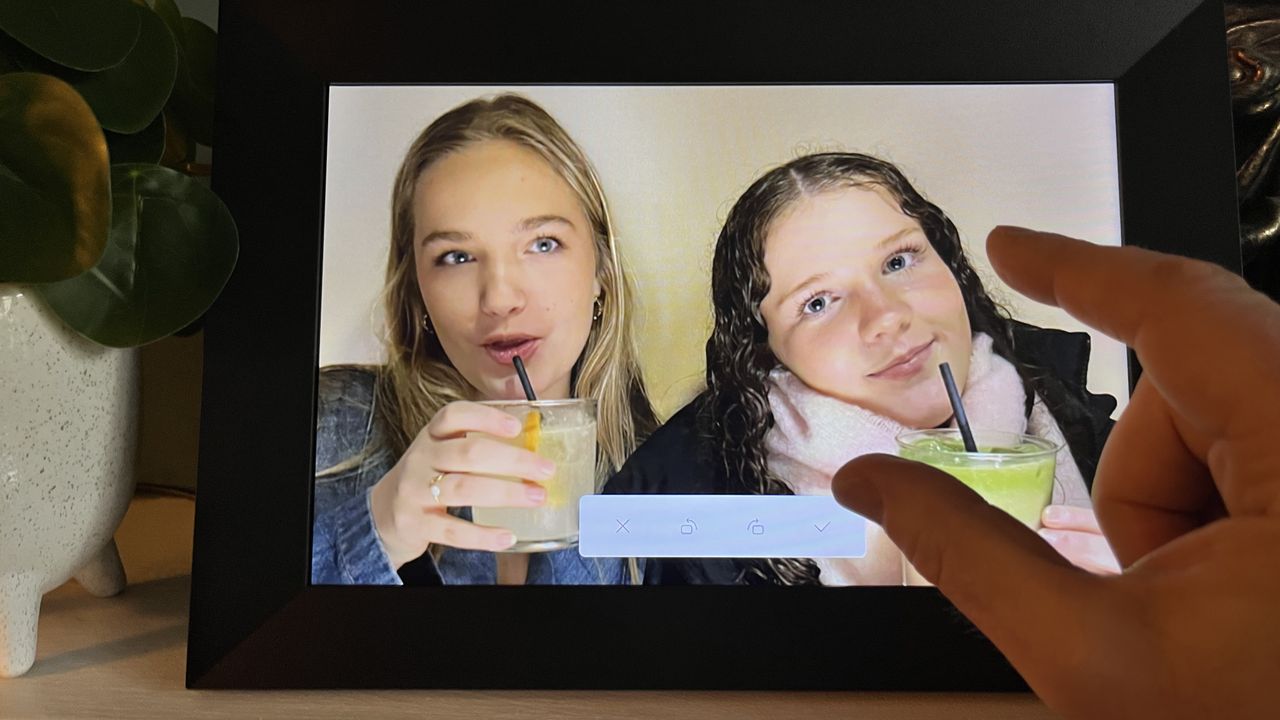 Aeezo 10.1-inch digital picture frame showing image of two girls sipping mocktails being recomposed with a pinch-zoom action