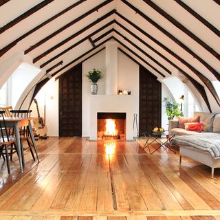 attic room with wooden floor and fireplace and tables and chairs