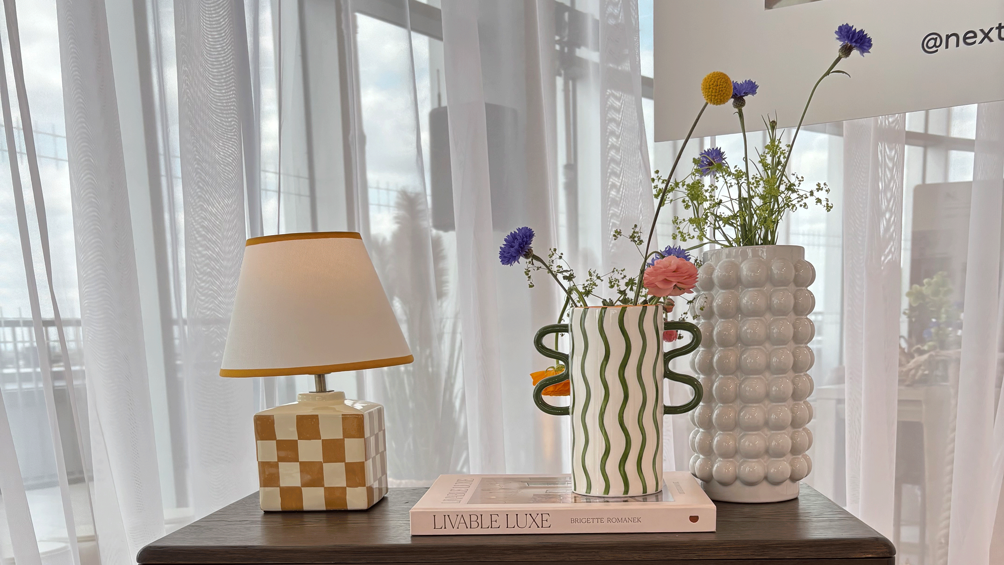 Yellow check table lamp, green wriggle vase and bubble vase on a dark wood side table