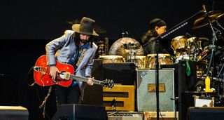 Mike Campbell performs with a red Gibson acoustic onstage during Fleetwood Mac's set at Pinkpop 2019.