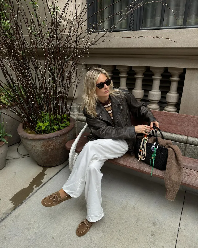 Woman in leather jacket, white jeans, and boat shoes