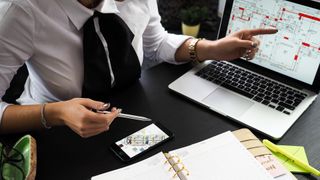 estate agent looking at housing plans on laptop and phone