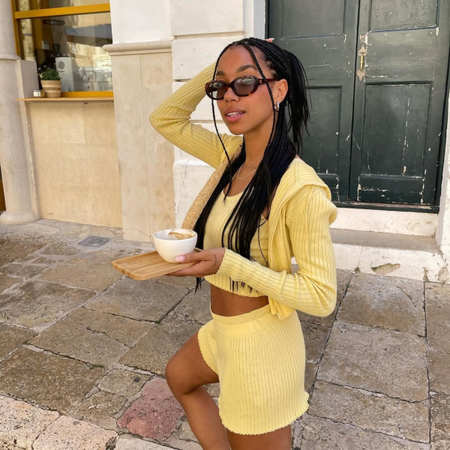 Amaka in a yellow cardigan and matching shorts