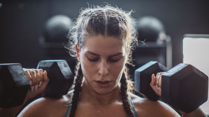 Woman lifting two dumbbells above her head