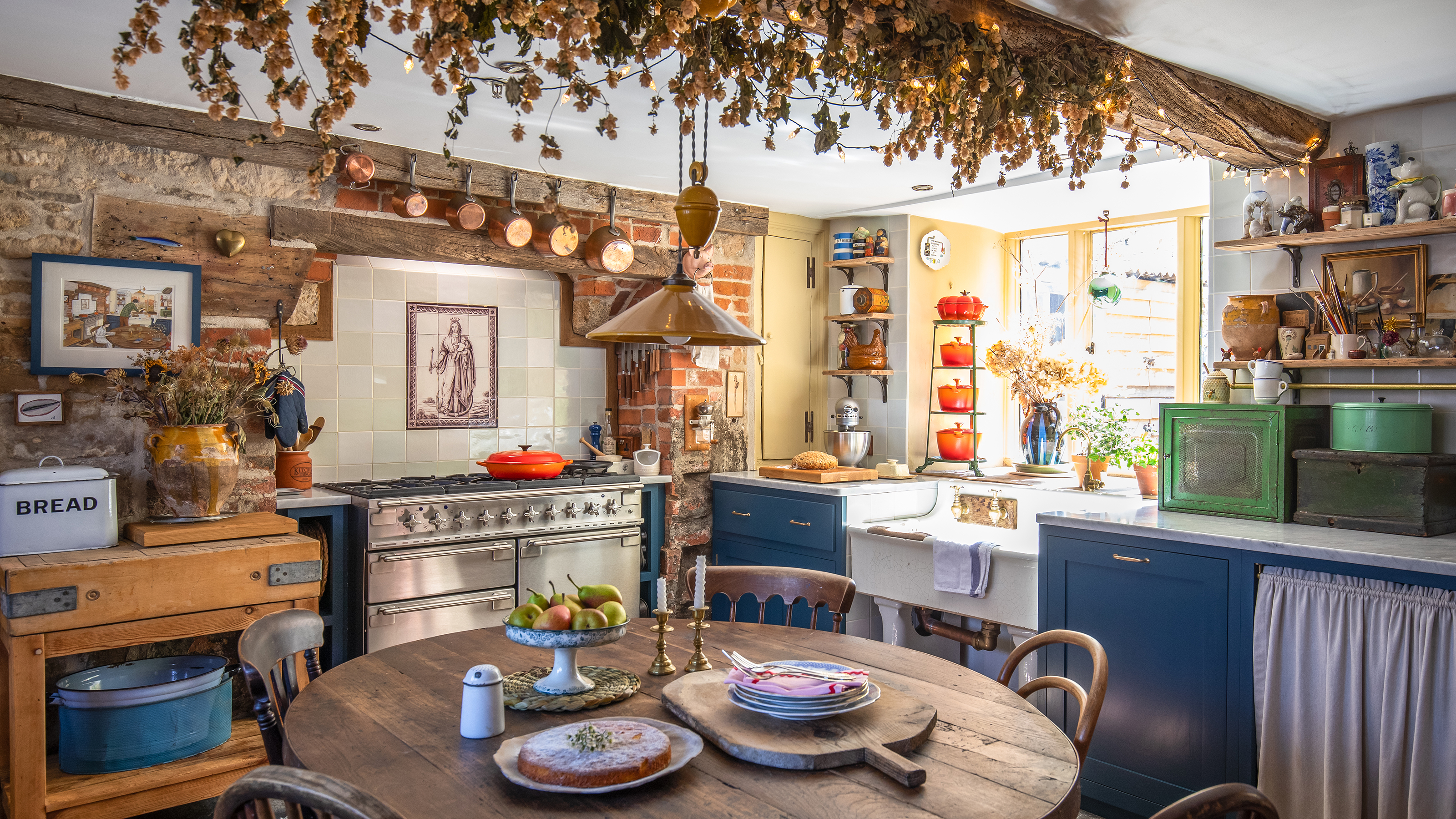 rustic style kitchen with mixed units, range cooker in inglenook, vintage pieces, hops on ceiling beam