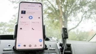 Echo Auto (2nd Gen) next to a phone running Auto Mode in the Alexa app