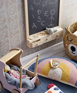 A small wall mounted chalkboard with drawers beside some colorful childrens toys