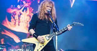 Dave Mustaine live onstage with his signature Gibson V, Megadeth mascot Vic Rattlehead is visible in the background