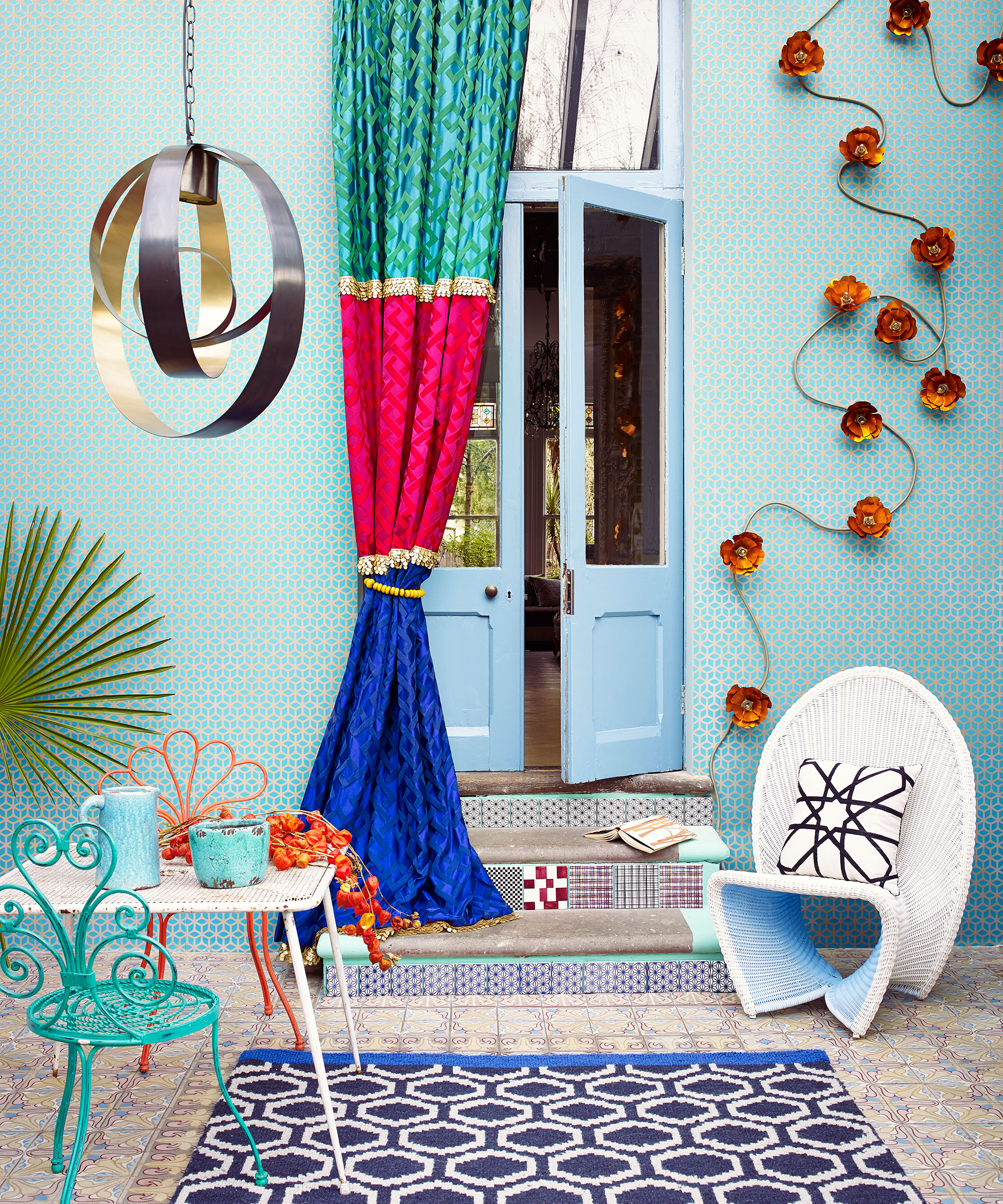 Colorful courtyard garden ideas example, with blue tiled walls, turquoise and orange chairs, a blue, turquoise and pink drape and orange decor.