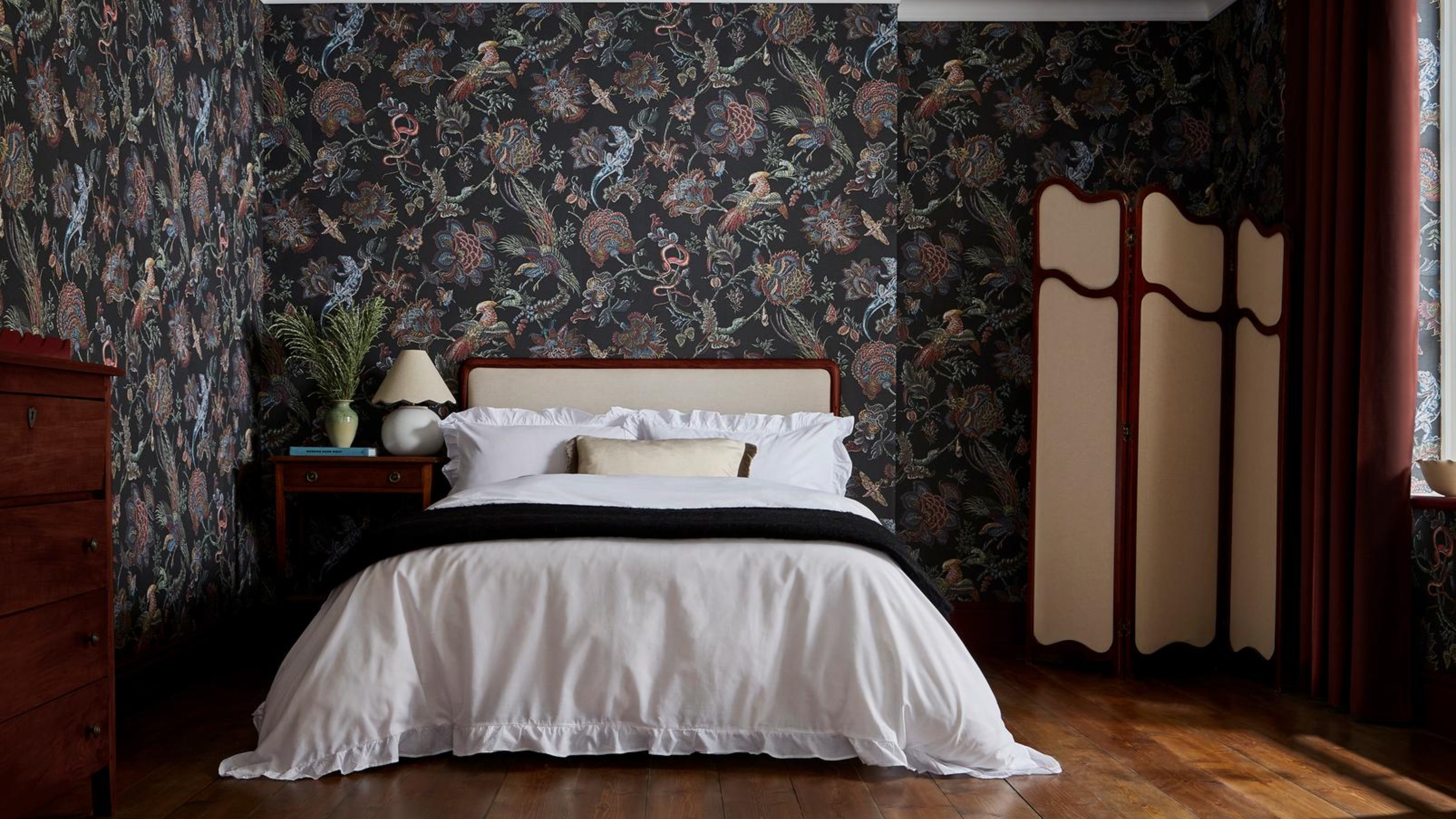 a bedroom with dark patterned wallpaper and traditional style furniture