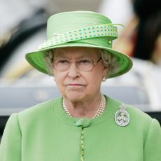 Queen Elizabeth II purses her mouth and looks annoyed while wearing a lime green coat dress and a matching hat in 2007