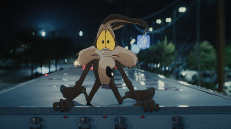 Wile E. Coyote looking scared while on the top of a truck in Coyote vs. Acme 