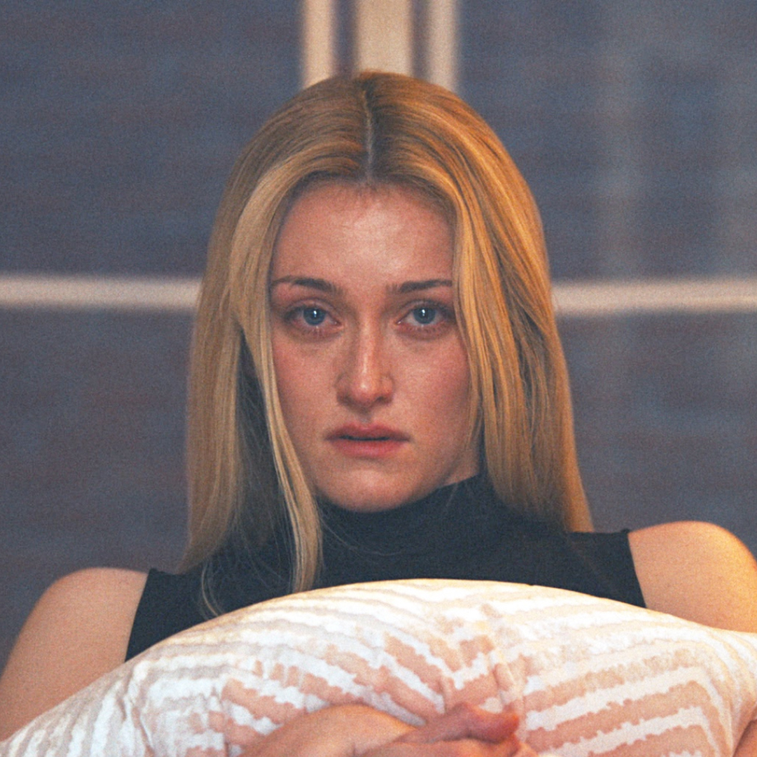 sarah pidgeon as carolyn bessette kennedy crying and hugging a pillow while watching the news about princess diana's death in fx's love story
