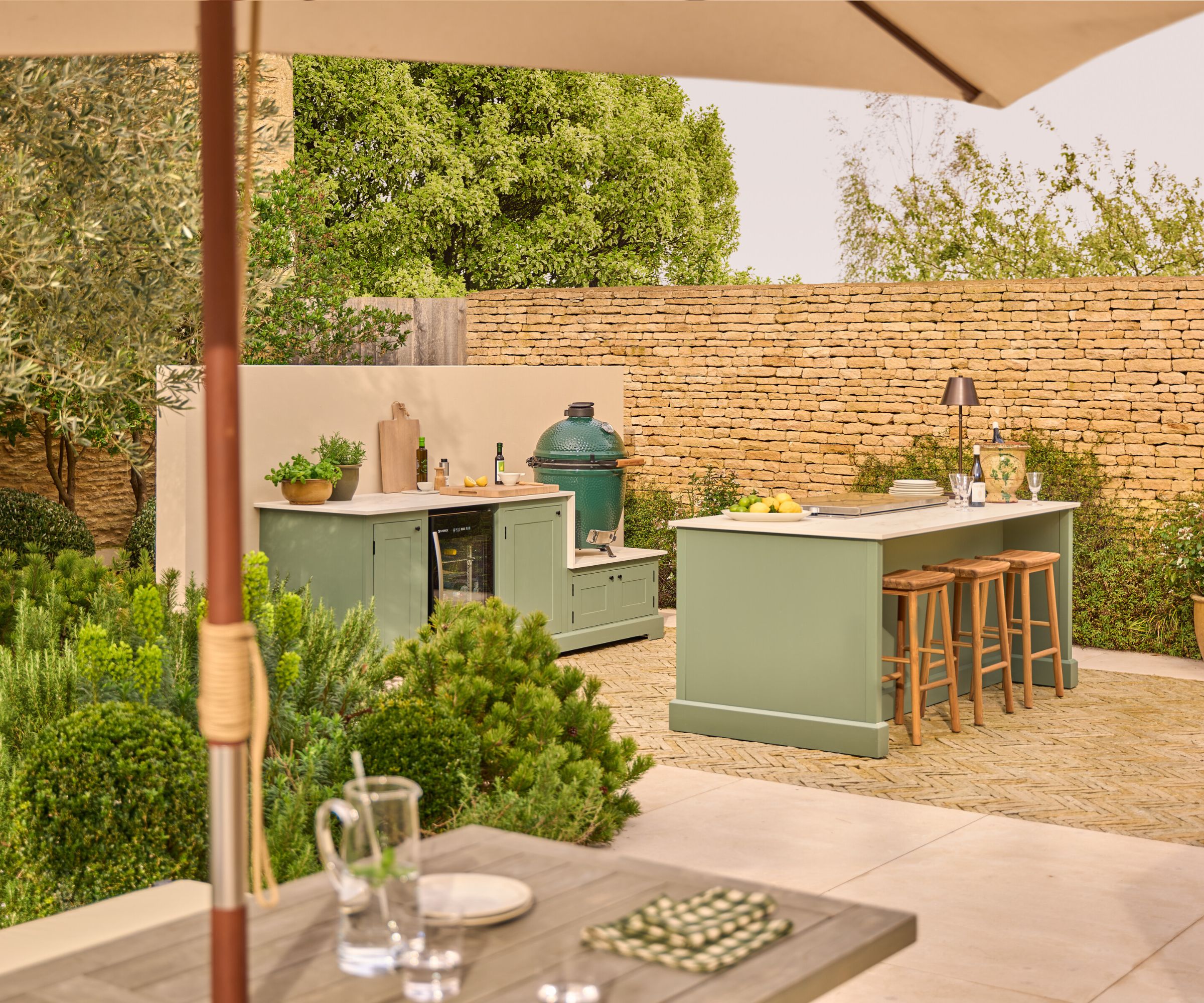 An outdoor kitchen with green cabinets and white countertops