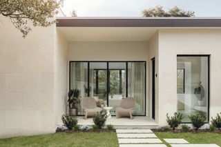 exterior of house with white walls and steel framed windows with outside seating area