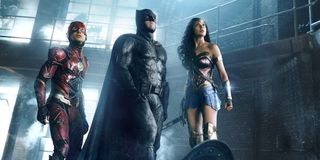 The Flash, Batman and Wonder Woman stand in an abandoned factory and look up in a scene from Justice