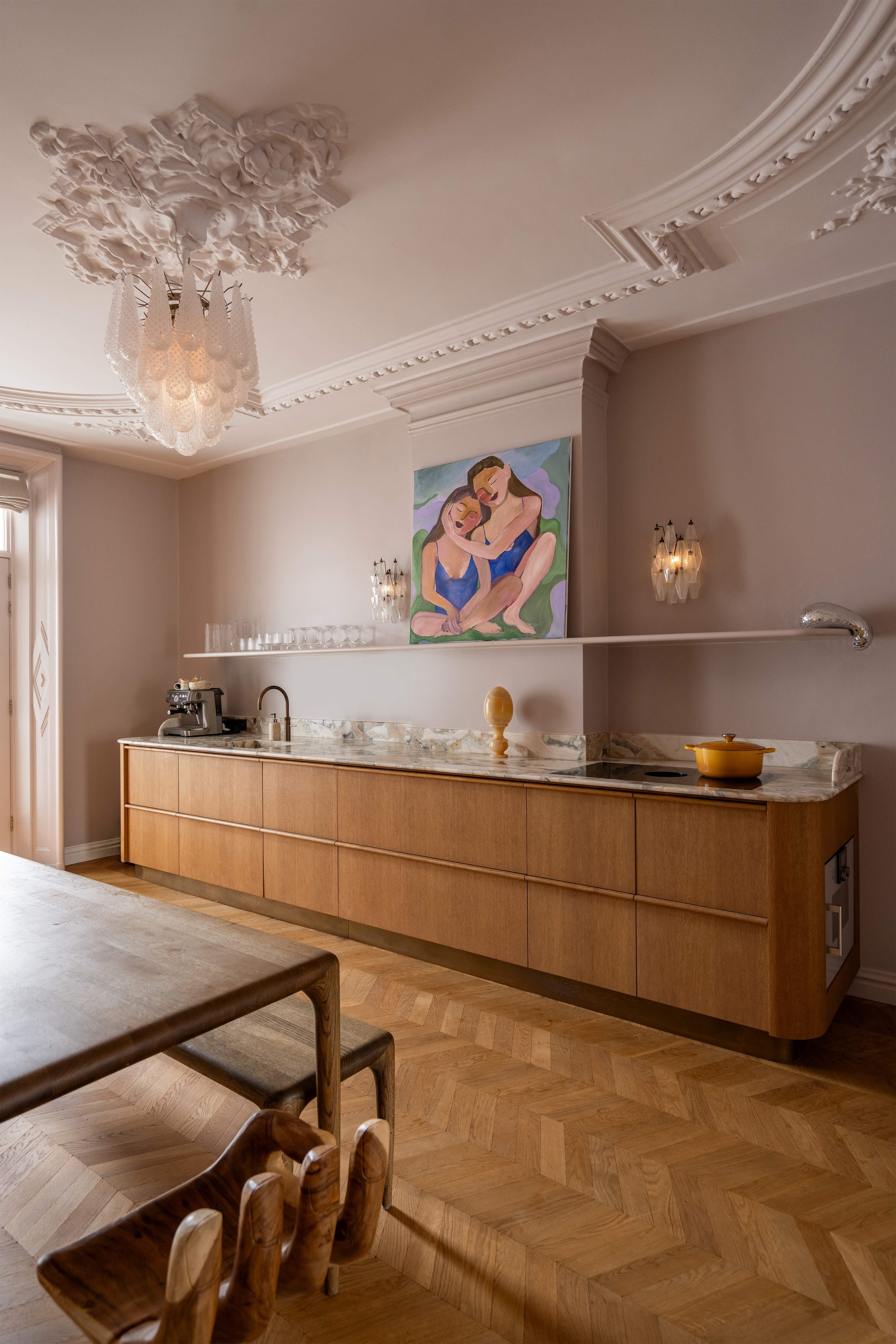 A one-wall kitchen with a wooden parquet flooring, decorated with two dainty wall sconces