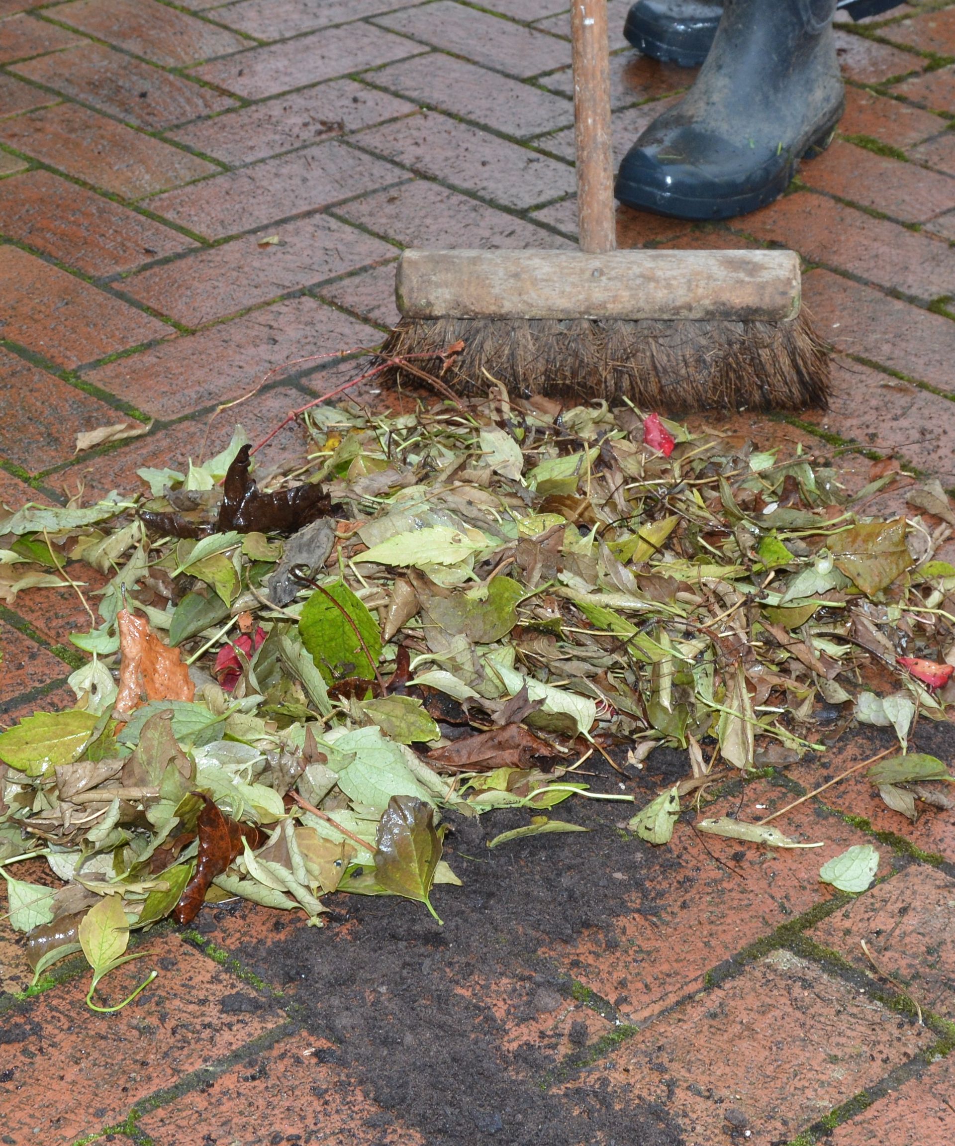 Brushing up patio debris before cleaning the bricks