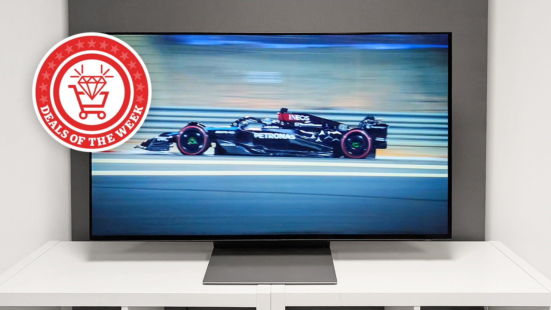 A picture of the Samsung S90F displaying an F1 car, with the deals of the week logo overlaid on top